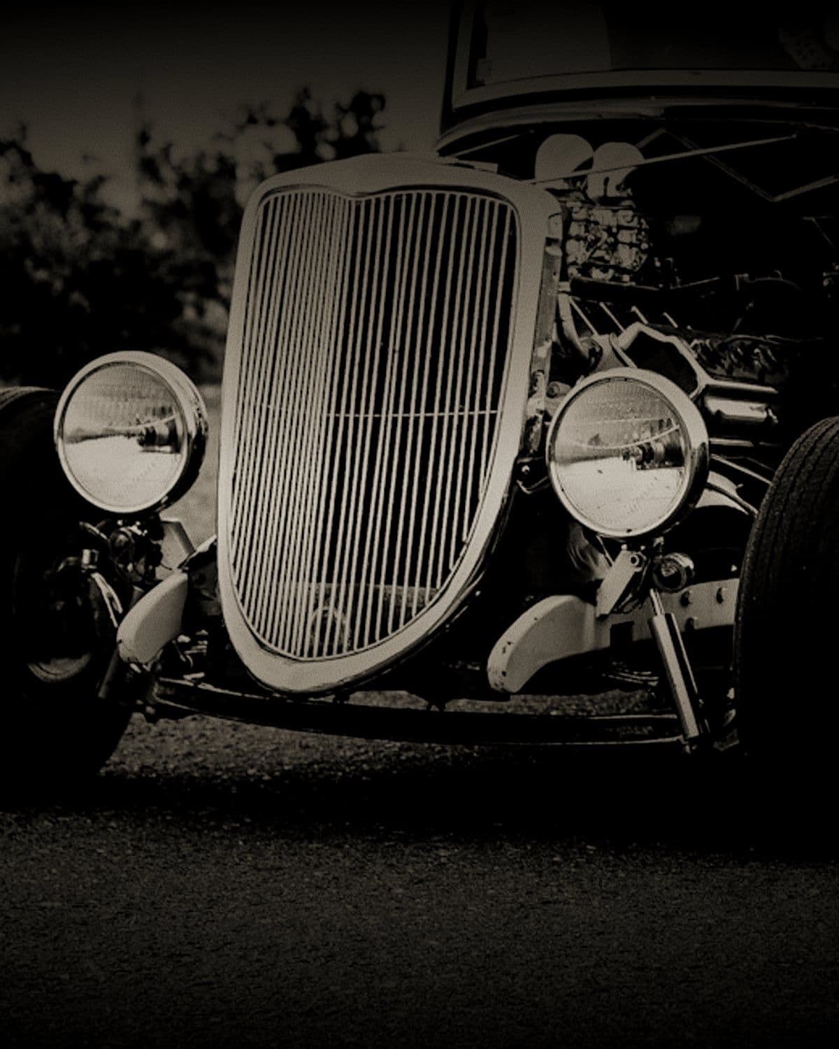 Radiator shell and headlamps of a 1930s coupé in low light